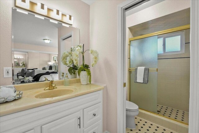 bathroom with toilet, an enclosed shower, and vanity