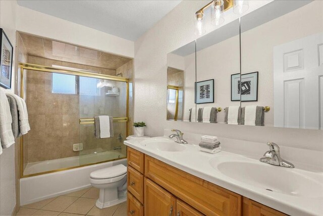 full bathroom featuring toilet, bath / shower combo with glass door, tile patterned floors, and vanity