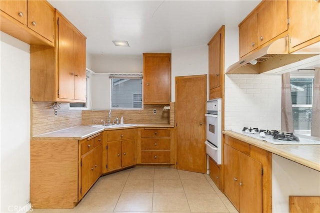 kitchen featuring sink, light tile patterned floors, white appliances, and tasteful backsplash