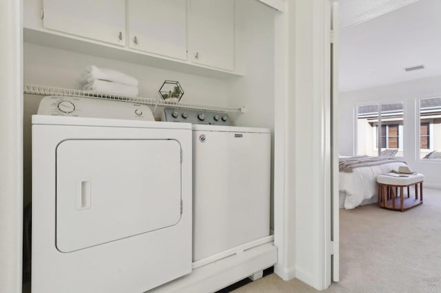 clothes washing area with light colored carpet, independent washer and dryer, and cabinets