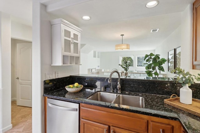 kitchen featuring dishwasher, sink, dark stone countertops, and white cabinetry