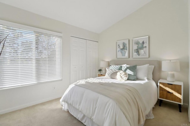 bedroom featuring a closet, light carpet, and vaulted ceiling