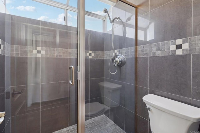 bathroom with tile walls, toilet, and walk in shower