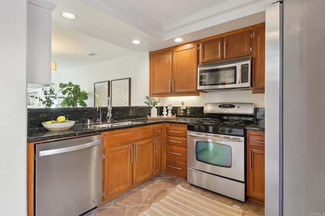 kitchen with light tile patterned floors, sink, appliances with stainless steel finishes, and dark stone countertops