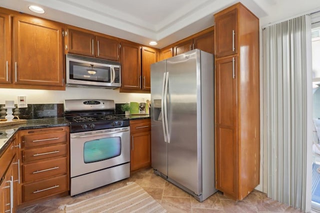 kitchen with appliances with stainless steel finishes and dark stone counters