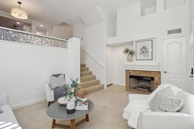 carpeted living room with a high ceiling and a tiled fireplace