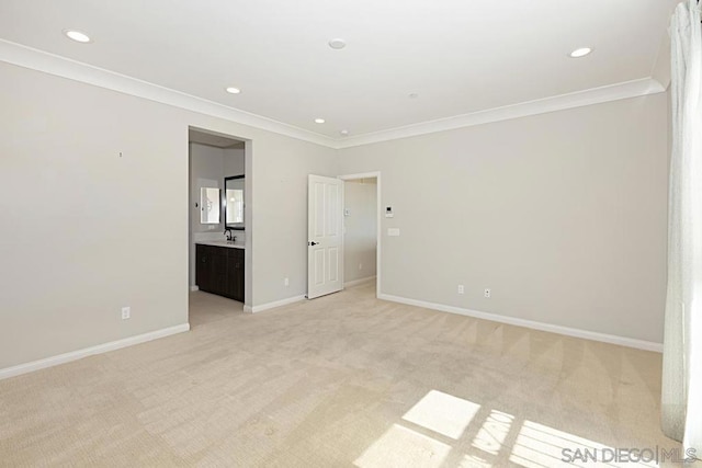 unfurnished bedroom featuring sink, connected bathroom, ornamental molding, and light colored carpet