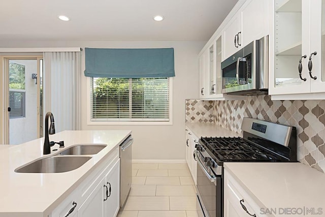 kitchen featuring a healthy amount of sunlight, backsplash, white cabinetry, appliances with stainless steel finishes, and sink