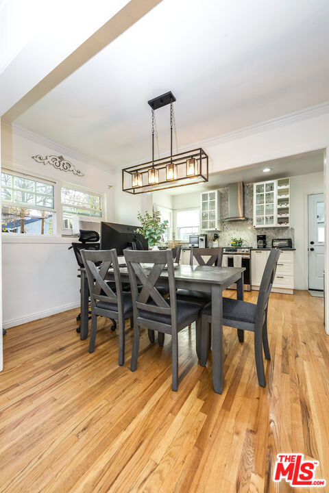 dining room with light wood-type flooring, a healthy amount of sunlight, and ornamental molding