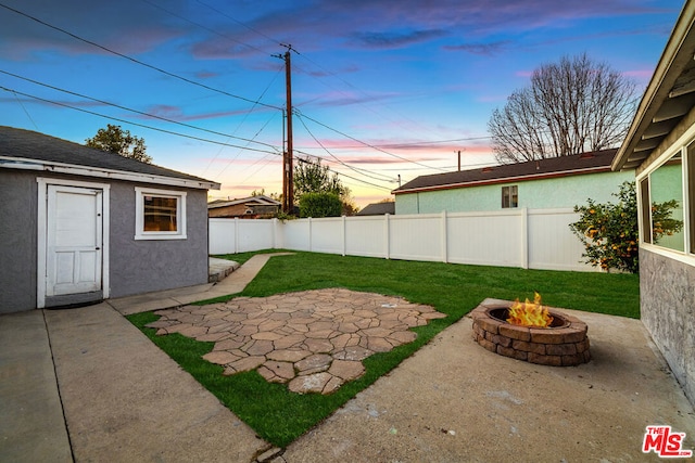 yard at dusk with an outdoor fire pit, a patio, and an outbuilding