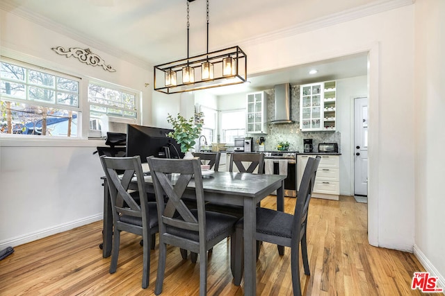 dining room featuring light hardwood / wood-style floors, crown molding, a chandelier, and sink