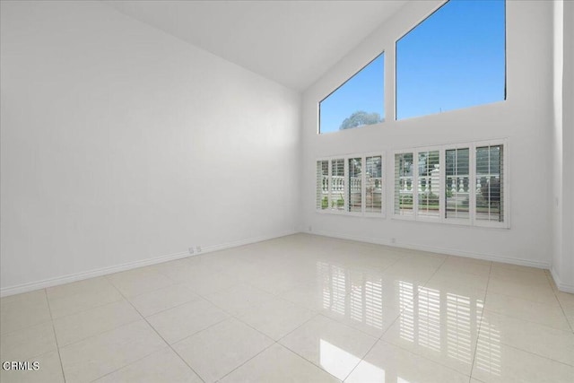 spare room featuring high vaulted ceiling and light tile patterned floors