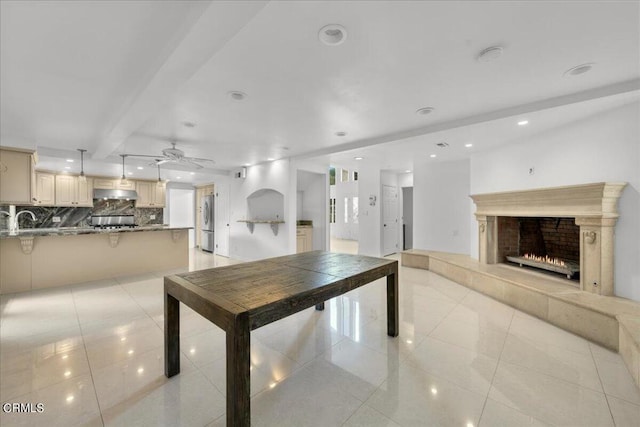 interior space with sink, a fireplace, ceiling fan, and light tile patterned floors