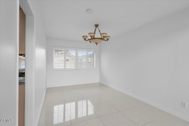 tiled spare room with a notable chandelier