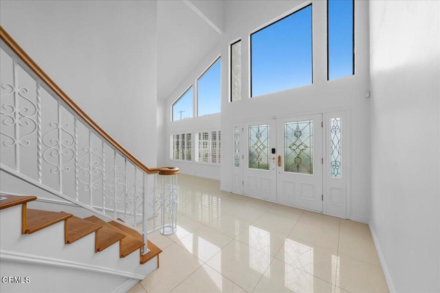 foyer with light tile patterned flooring, french doors, and a towering ceiling