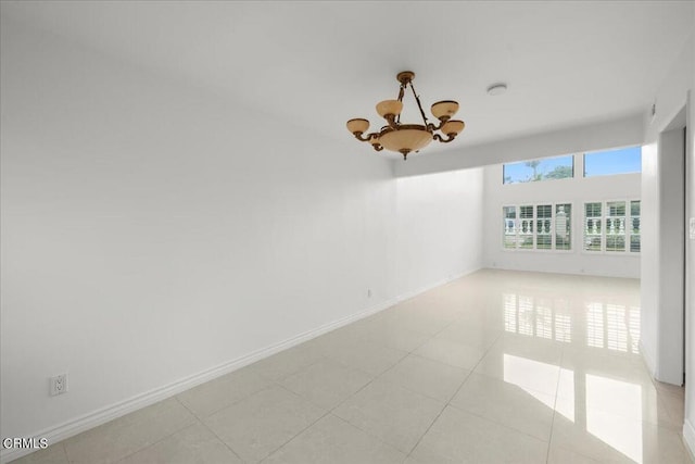 empty room featuring an inviting chandelier and light tile patterned floors