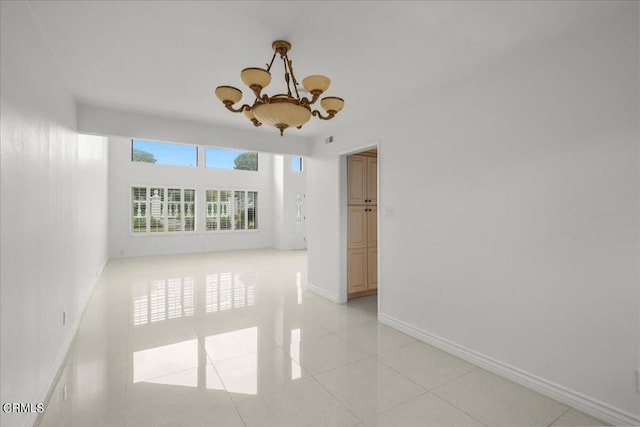 tiled empty room with an inviting chandelier