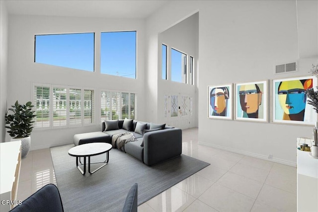 living room with a towering ceiling and light tile patterned floors