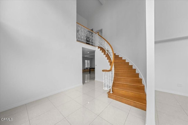 stairway with a high ceiling and tile patterned flooring