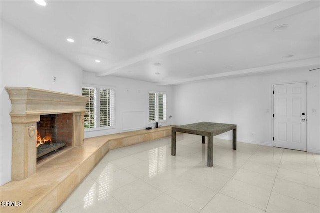 playroom featuring a fireplace, light tile patterned floors, and beam ceiling