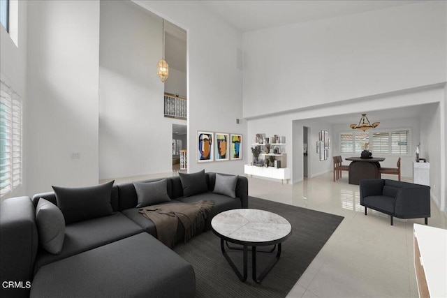 living room with a high ceiling, a notable chandelier, and tile patterned floors