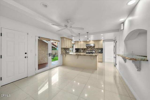 kitchen featuring light brown cabinets, light tile patterned floors, kitchen peninsula, range, and hanging light fixtures