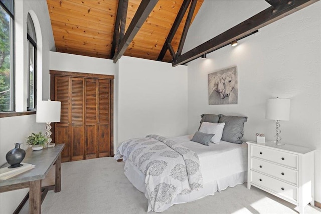 carpeted bedroom with lofted ceiling with beams, wooden ceiling, and a closet