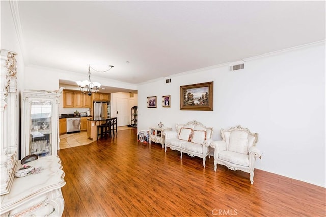 living room with light hardwood / wood-style floors, an inviting chandelier, and ornamental molding