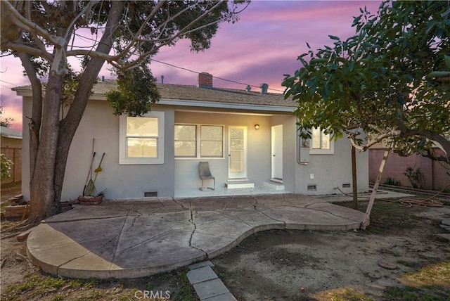 back house at dusk featuring a patio