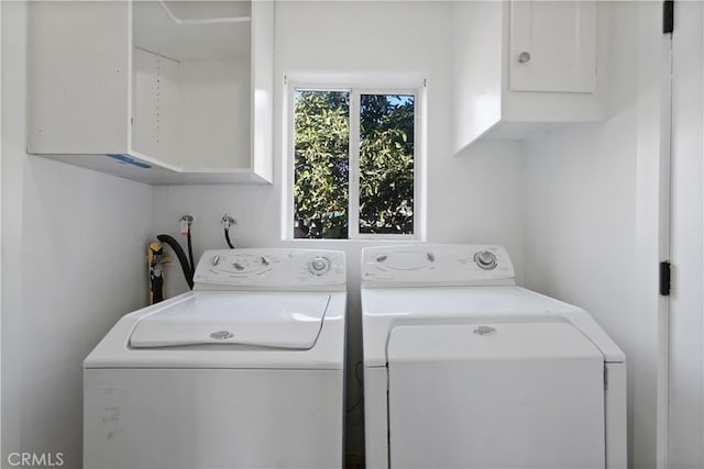 clothes washing area with washer and dryer, cabinets, and a healthy amount of sunlight