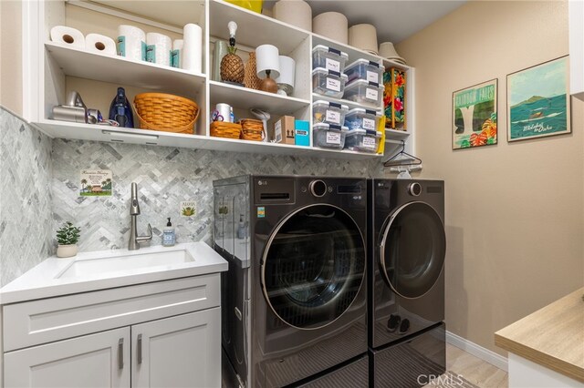 laundry area with cabinets, separate washer and dryer, and sink