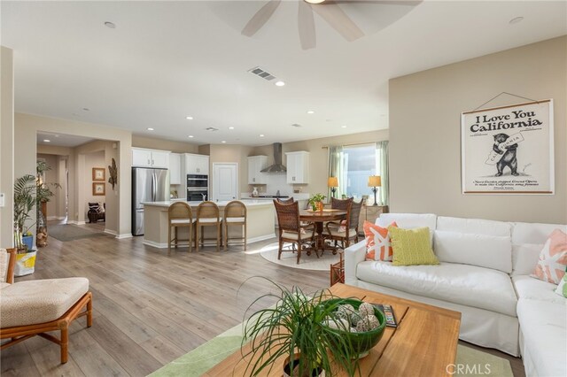 living room with ceiling fan and light hardwood / wood-style flooring