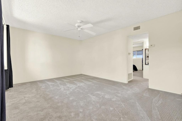 spare room featuring light colored carpet, a textured ceiling, and ceiling fan