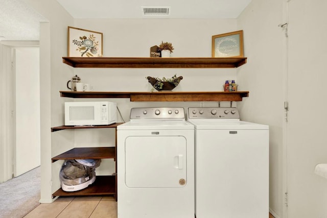 clothes washing area with independent washer and dryer and light colored carpet