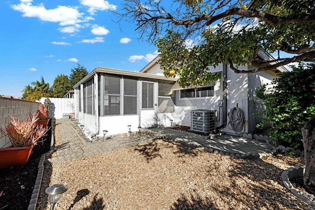 rear view of house featuring central air condition unit and a sunroom