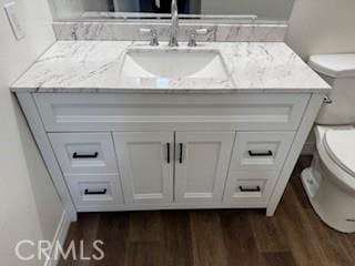 bathroom with toilet, wood-type flooring, and vanity