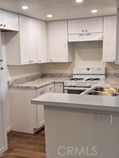 kitchen with dark hardwood / wood-style flooring, white cabinetry, white range with gas stovetop, and kitchen peninsula