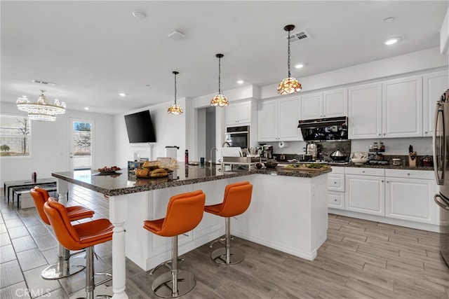 kitchen featuring appliances with stainless steel finishes, white cabinets, a kitchen breakfast bar, and a spacious island