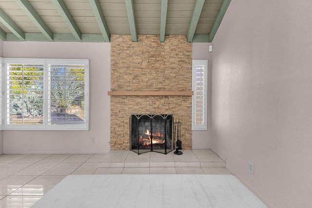 unfurnished living room featuring vaulted ceiling with beams, tile patterned floors, and a stone fireplace