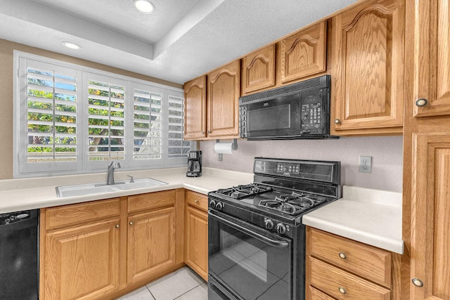 kitchen featuring a textured ceiling, black appliances, sink, light tile patterned floors, and a tray ceiling