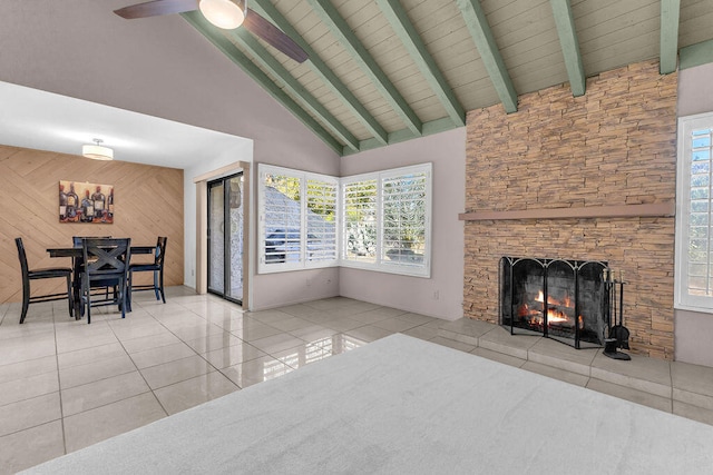 living room with a fireplace, beam ceiling, light tile patterned flooring, wooden walls, and high vaulted ceiling