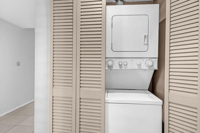 clothes washing area featuring stacked washing maching and dryer and light tile patterned floors