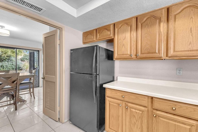 kitchen featuring black fridge and light tile patterned flooring