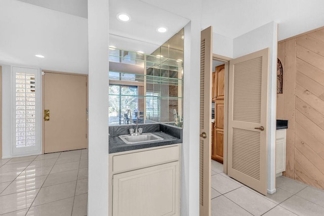 interior space featuring tile patterned flooring, wood walls, and vanity