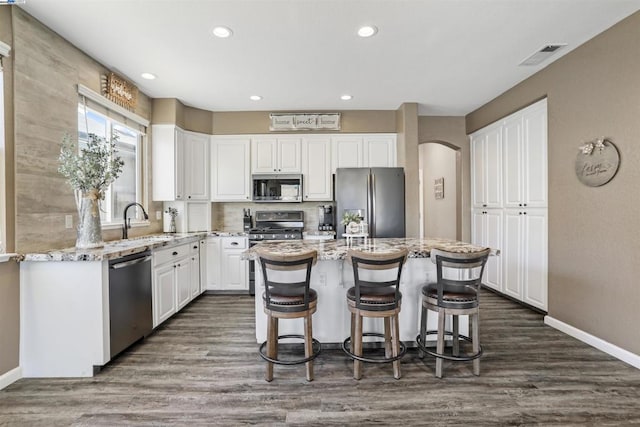 kitchen featuring appliances with stainless steel finishes, white cabinetry, a kitchen bar, and a kitchen island