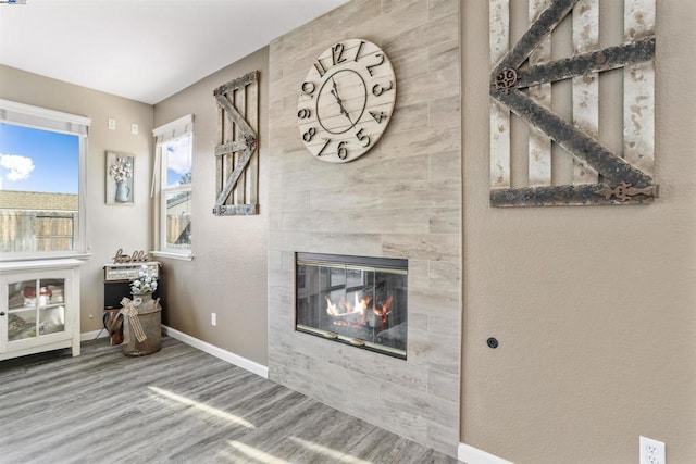 unfurnished living room featuring a tiled fireplace and wood-type flooring