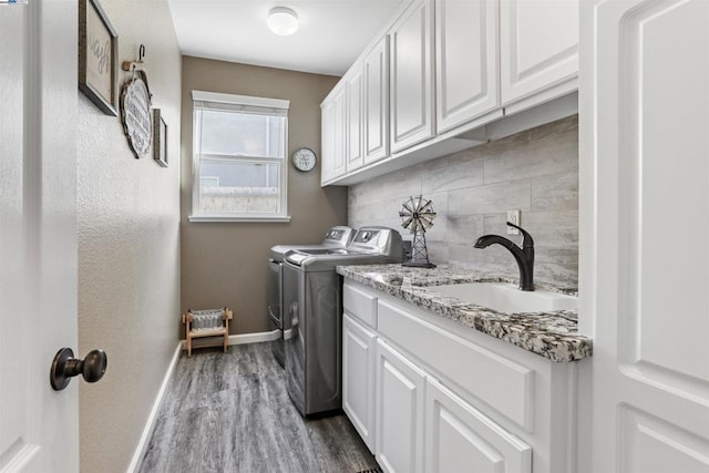 clothes washing area with sink, cabinets, hardwood / wood-style floors, and washing machine and clothes dryer