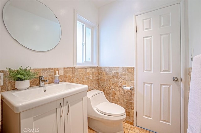 bathroom featuring toilet, tile patterned floors, vanity, and tile walls