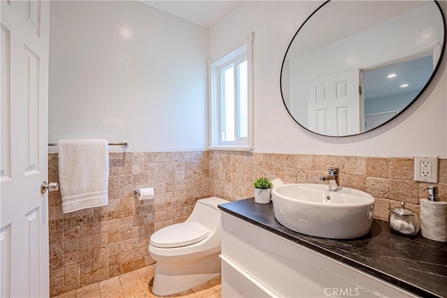 bathroom with tile walls, tile patterned flooring, vanity, and toilet