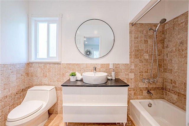 full bathroom featuring tile walls, vanity, tiled shower / bath combo, and toilet